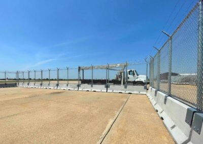 AOA temporary fence installation with concrete barriers, chain-link panels, and barbed wire, providing secure perimeter protection for airport operations.