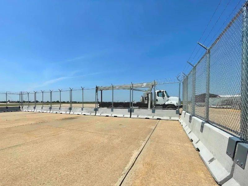 AOA Temporary Fence Installation | Vector Fence AOA temporary fence installation with concrete barriers, chain-link panels, and barbed wire, providing secure perimeter protection for airport operations.