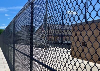 Commercial black vinyl-coated chain link fence installation providing security and durability for business and industrial properties.