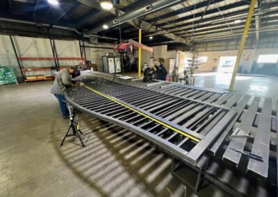 Vector Fence technician measuring and fabricating a custom steel gate in a professional shop, ensuring precise fit and long-term durability.