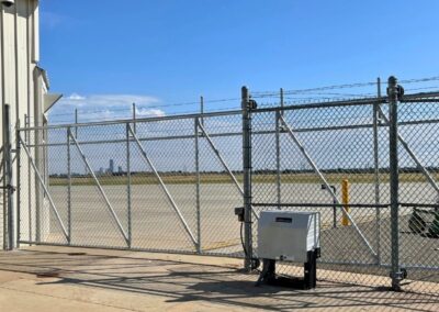 Commercial automatic chain-link driveway gate with reinforced steel framing and gate operator, showcased as an example of what Vector Fence can install.