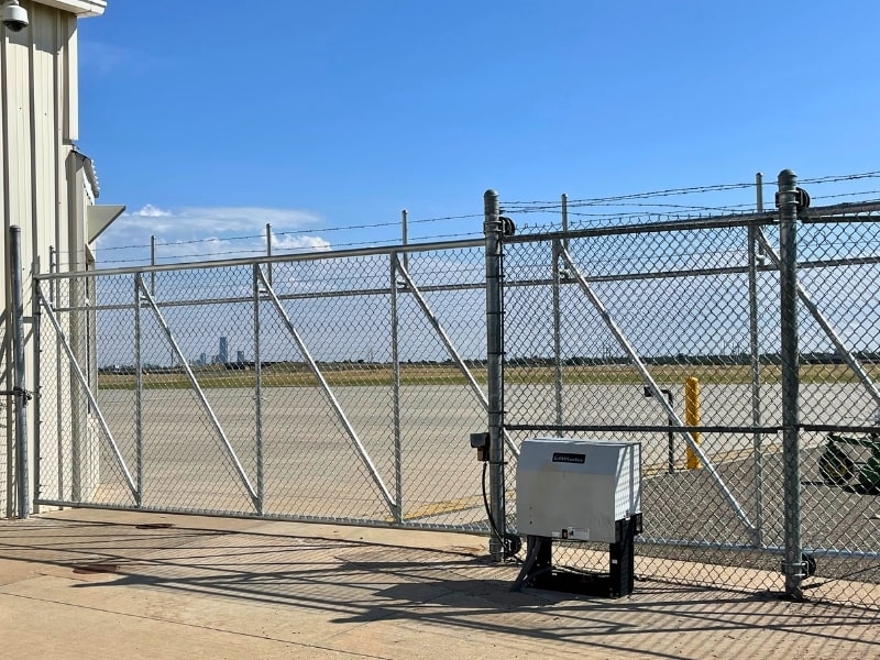 Commercial automatic chain-link driveway gate with reinforced steel framing and gate operator, showcased as an example of what Vector Fence can install.