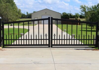 Custom residential automated driveway gate with decorative iron design, showcasing a secure and stylish entry for a home property.