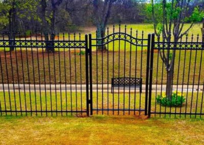 Custom ornamental iron walk gate with decorative scrollwork and matching fence panels, showcasing a stylish and durable residential entry gate.