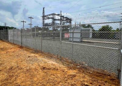 High-security chain link fence with barbed wire installed around an electrical substation for commercial perimeter protection.