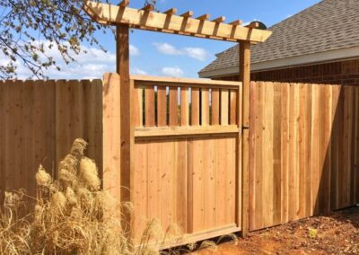 Residential cedar fence with a custom steel frame gate and decorative arbor showcasing Vector Fence’s custom wood fence installation services.