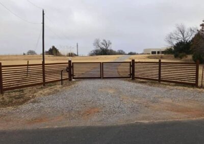 Rural automatic driveway gate with horizontal steel slats and matching fence line, showcasing a durable and stylish access solution for country properties.