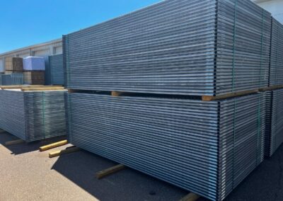 Stacked galvanized temporary fence panels stored at a Tulsa facility, ready for commercial and construction site use.