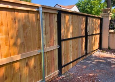 Residential double drive-through steel frame gate installed with a cedar privacy fence, showcasing a strong and durable entry designed for vehicle access.