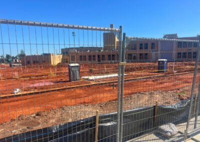 Temporary construction fence installed around an active building site, providing secure perimeter control and public safety during ongoing construction.