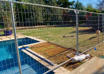Temporary fence panels installed between residential backyards to create a safe barrier around a pool and separate adjoining properties.