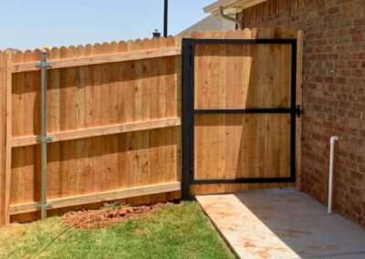 Residential walk-through steel frame gate installed with a cedar privacy fence, showcasing a durable and reinforced entry point for long-term stability.