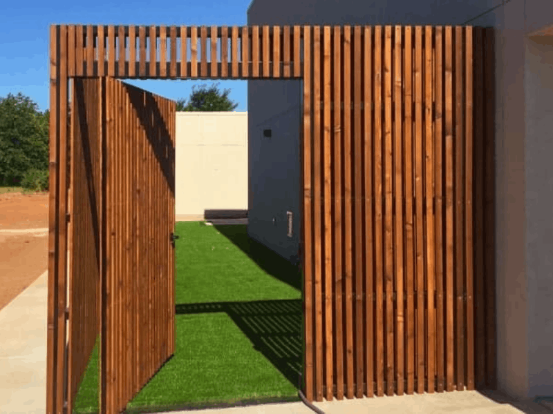 Custom cedar fence gate with vertical wood slats creating a modern entryway and private outdoor access area.