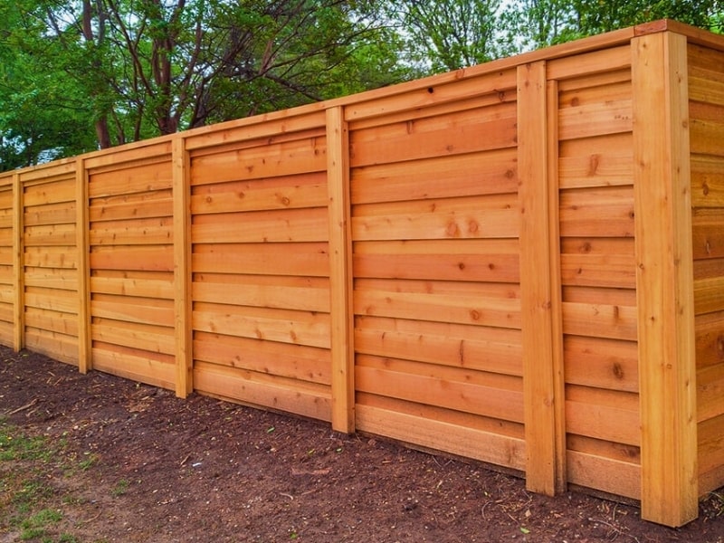 Horizontal cedar privacy fence installation with framed posts creating a modern wood privacy fence design for a residential property.