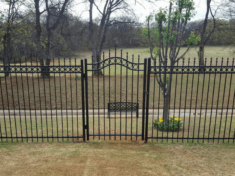 Backyard Ornamental Iron Fence with Walk Gate | VectorFence.com Backyard ornamental iron fence with a walk-through gate, arched design, decorative finials, and open view fencing.