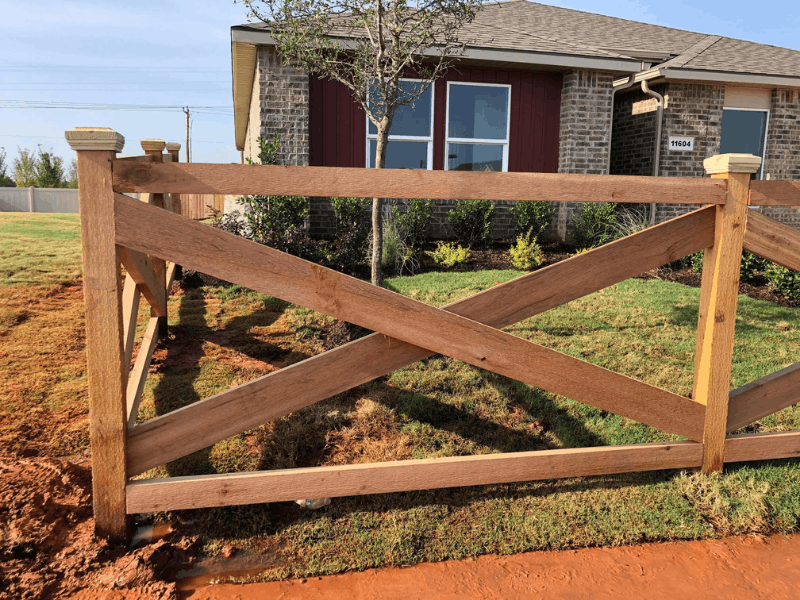Post and rail cedar fence with crossbuck wood rails installed in front of a residential property for open boundary fencing.