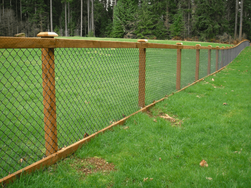 Wood and Chain Link Fence | VectorFence.com Wood-framed chain link fence installed along a large grassy property for open visibility, durability, and a natural finished look.
